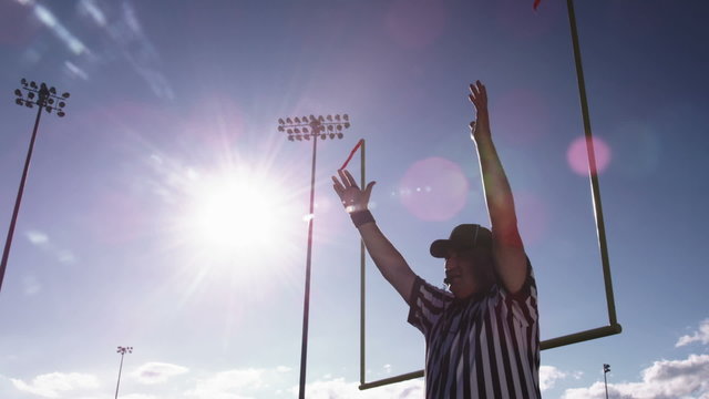 A football referee raises hands over his head for a field goal