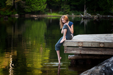 pretty teen girl on a lakeside dock in summer