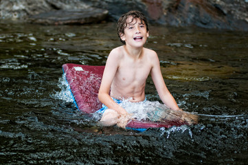 young boy playing in a lake with a boogie board