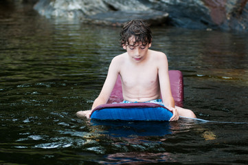 young boy playing in a lake with a boogie board