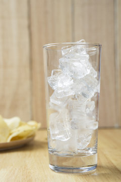 Glass with ice on wooden background