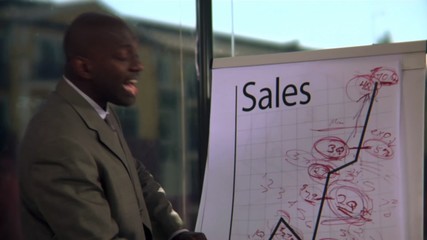 A business man leads a meeting and presents his chart