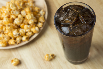 Cola with Ice and Popcorn on a wooden background