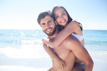 Fototapeta premium Handsome man giving piggy back to his girlfriend