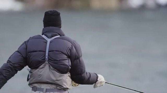 Wide shot of a man standing in a river and fly fishing