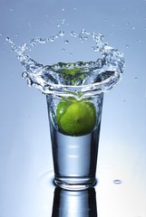 glass with lemon splashing into water isolated on white.