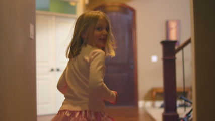 A little girl dances through the hallway while looking back - Powered by Adobe
