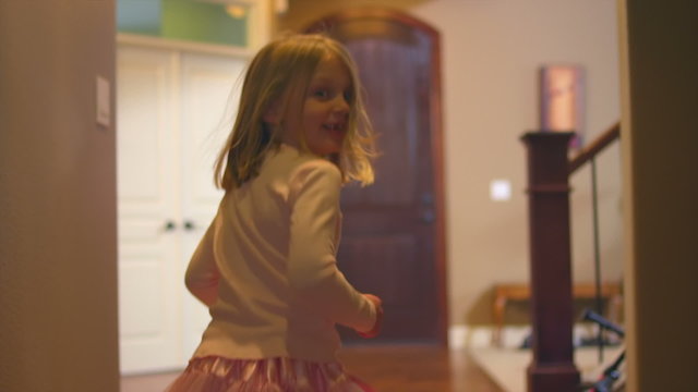 A little girl dances through the hallway while looking back