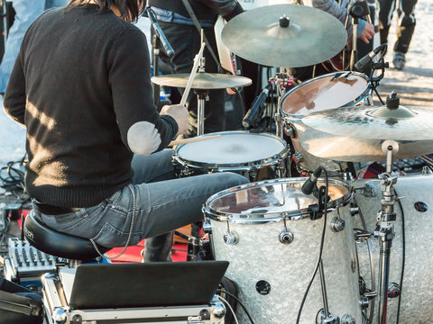 black hair drummer during outdoor concert: rear view