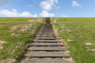 Wooden stairs upon green hill with blue sky