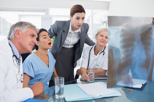 Team of doctors and businesswoman examining xray 