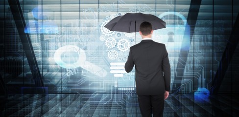 Composite image of businessman sheltering under black umbrella