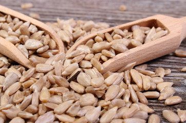 Sunflower seeds with spoon on wooden background