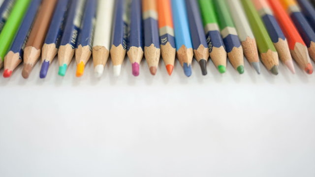 Colored wooden pencils on white paper