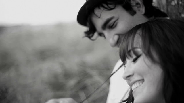 A young couple sit and spend time together in a field