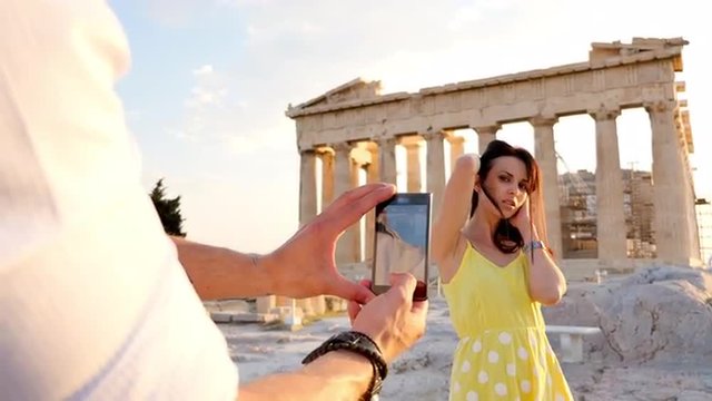 Beautiful Greek woman poses for a photo in front of a Greek temple.
