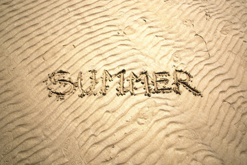 Bright sunny summer word handwritten on sand