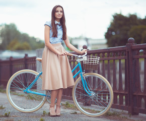 Fototapeta na wymiar Young beautiful, elegantly dressed woman with bicycle