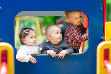 Fototapeta na wymiar Three babies in toy car on the playground