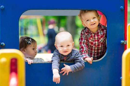Three babies in toy car on the playground