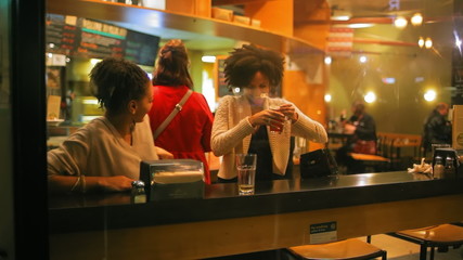 Two pretty young woman meet up for a drink at a local pizza place