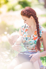 Beautiful happy mother breastfeeding outdoor