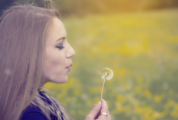 Pretty girl blowing a dandelion