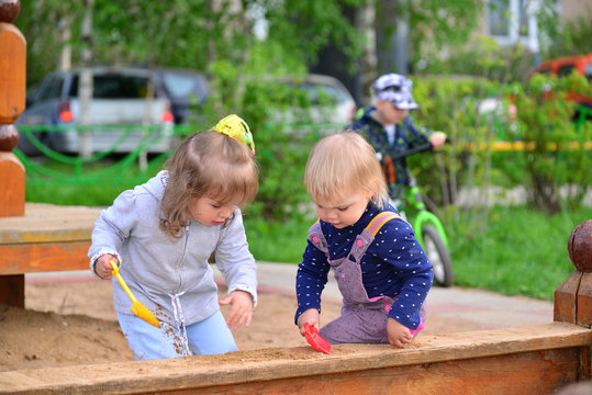 Two little sisters playing in  sandbox