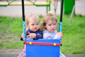 Fototapeta na wymiar Two little girl on swing ride