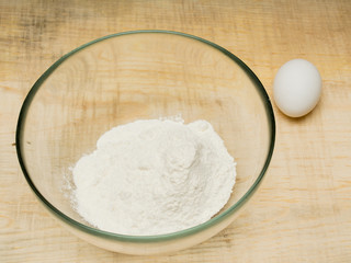 Bowl of flour and white egg on a wood kitchen table