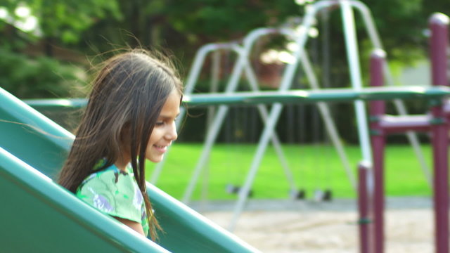Adorable little girl goes down a slide right into her father's arms. 
