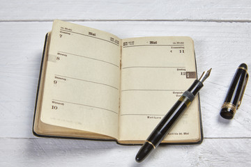 Antike Füllfeder und alter Kalender auf weißem Schreibtisch - 83998166