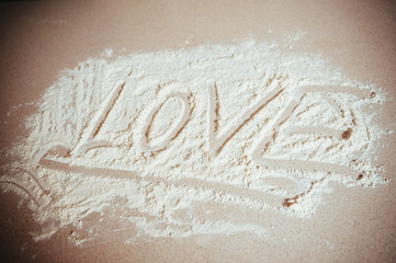 Inscription "LOVE" made by hand on sprinkled flour 