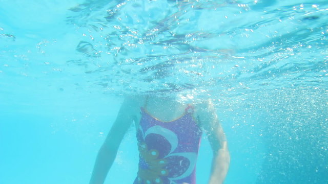 Underwater shot of a young girl jumping into the pool