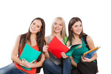 three students girl with copybooks sitting together on a white