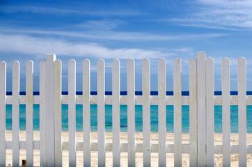 white fence on the beach with blue sea