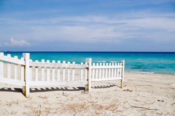 white fence on the beach with blue sea