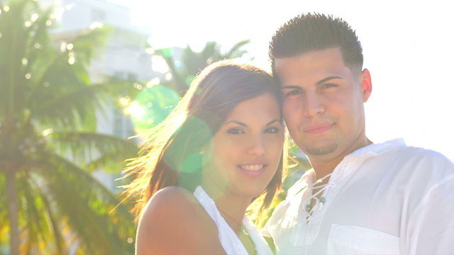 A young couple look to the camera with the sun behind them