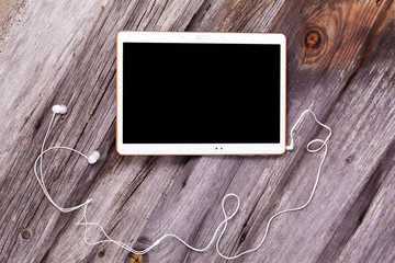 Digital tablet computer with earphones against wooden background