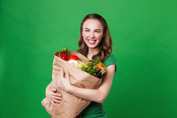 young woman holding a grocery bag full of fresh and healthy food