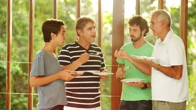 Men talking and eating at a Brazilian family BBQ