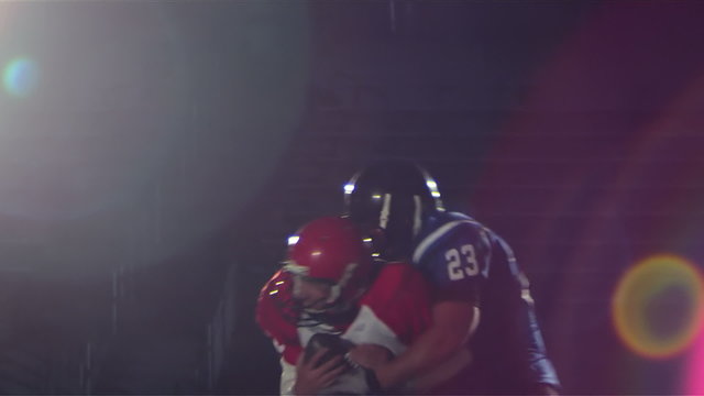 A quarterback receives ball snap and then gets sacked by a defender