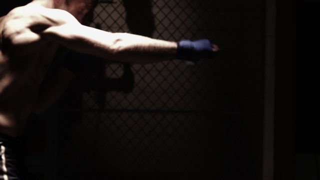 Caucasian male warms his muscles by shadow boxing. Medium shot.