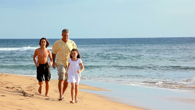 A family running through the waves on a beach in Hawaii