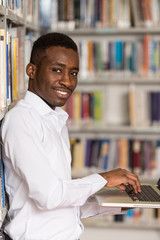 Naklejka premium Happy Male Student With Laptop In Library