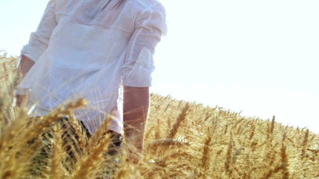 A cute woman walks through a vast field as seen from a low angle