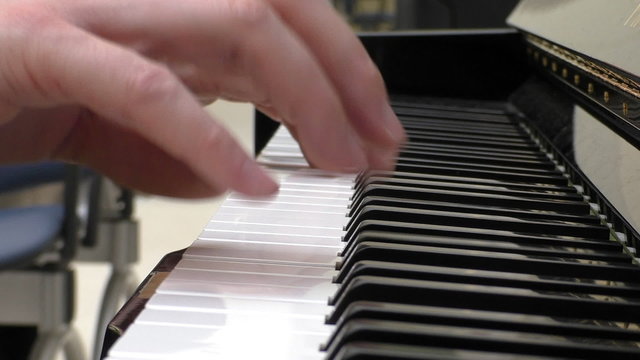 Close up of hands of a man  playing piano, side view.