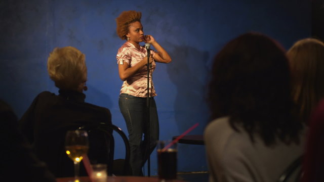 A young woman is up on stage giving a comedy performance