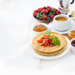 crepes with strawberry, jams, honey and white wooden background