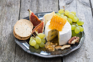 fresh camembert with honey, grapes and crackers on a plate